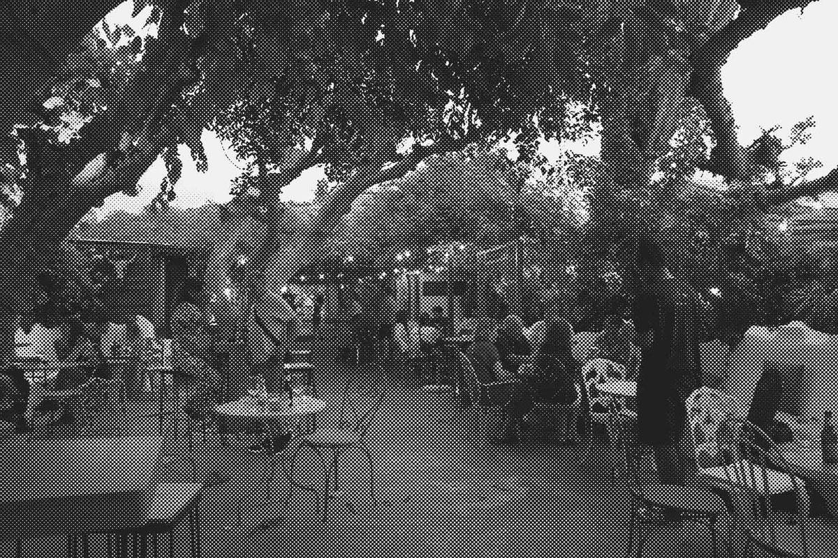 Outdoor patio of La Cochera Club, with tables under the trees